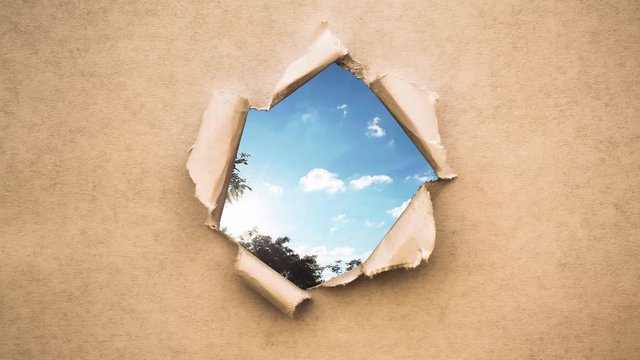 Creative 4k time laps video of fast moving clouds in the blue sky at sunset witn sunflare that are visible through a circle hole with torn edges in old retro grunge vintage paper.