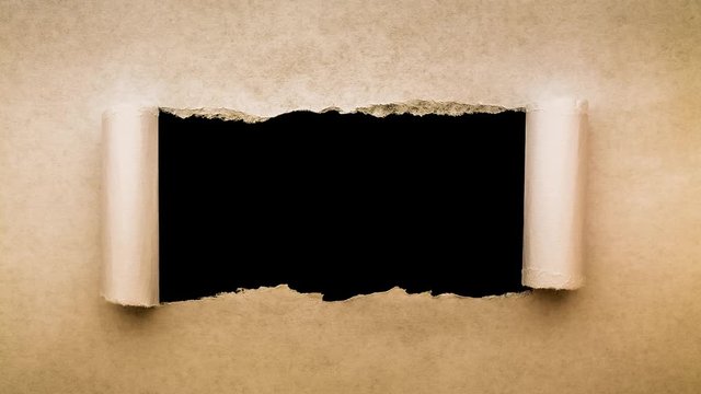 Creative 4k time laps video of a glowing full moon in the night sky with floating clouds, which is visible through a hole with torn edges in old retro grunge vintage paper.
