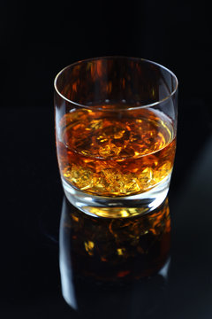 glass of whiskey with ice on black background