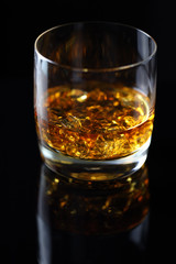 glass of whiskey with ice on black background