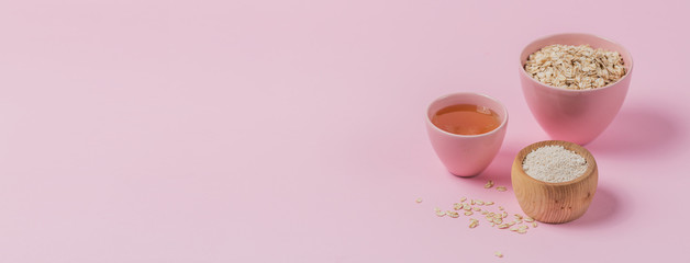 Bowl of dry oat flakes, oatmeal and honey on light background.