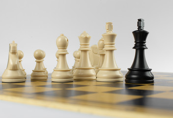 White figures against black king on a chessboard on isolated white background