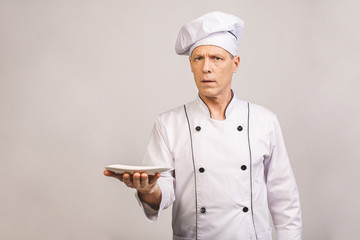 Portrait of senior chef holding empty dish isolated on white background.