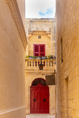 tiny street leading to red door in Mdina