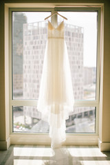 A white wedding dress hanged on the hanger. Buying a wedding dress.
