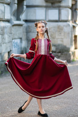 Fototapeta na wymiar Young girl with two pigtails, portrait of a girl with pigtails, a girl in a red dress on a walk