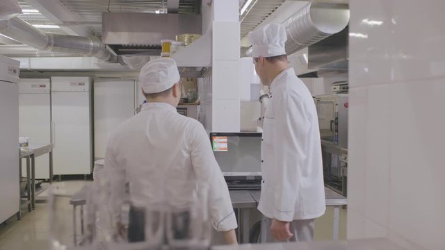 happy male chef and cook talking at restaurant kitchen