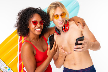 Cute woman and a caucasian man stands with big rubber mattress with their phones isolated on white background