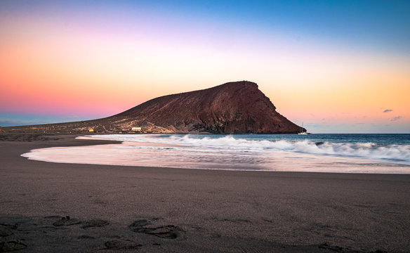 Colorful sky after sunset at La Tejita beach with the iconic "Red Hill" (La Montaña Roja) in the South of Tenerife, Canary Islands, Spain.