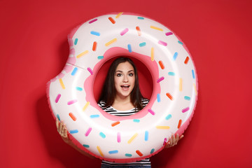 Young girl with inflatable donut on red background