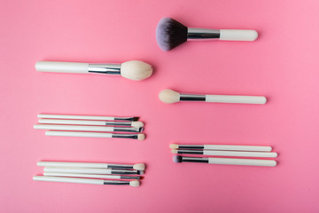 white makeup brushes on a pink background