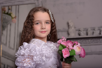 cute girl princess with curly hair and flowers in her arms, brunette with long hair, a child