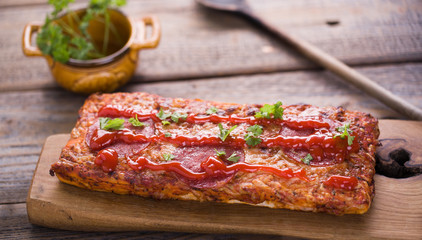 Delicious casserole with salami on wood