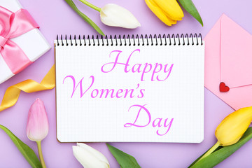 Text Happy Womens Day with tulip flowers, gift box and envelope on purple background