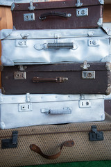 Vintage weathered leather and metal suitcases on top of each other. Retro. Background