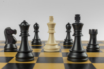 White figure in the center and blacks around on a chessboard on isolated white background