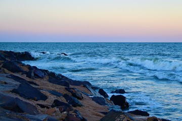 Ocean waves hitting rocks at sunset landscape