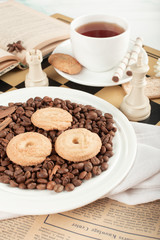 A cup of tea and a biscuit platter with some chess figures on a chessboard