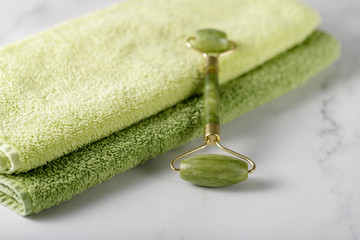 Jade facial roller for anti-aging skin massage on a marble table