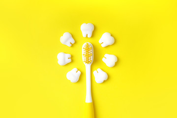Toothbrush with teeth models making sun on a yellow background. Dental concept.