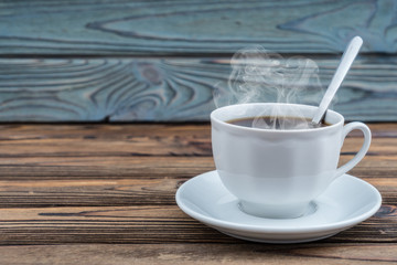 Cup of hot coffee on a wooden table background. Copy space