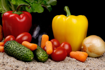 Composition of various juicy vegetables on the sand.