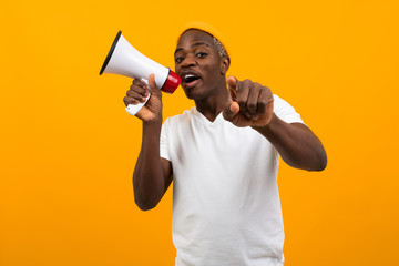 black african man speaks in megaphone on isolated yellow background