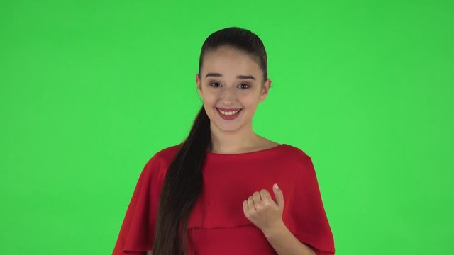 Portrait of pretty young woman is waving hand and showing gesture come here. Green screen