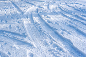 Top view of road covered by snow. Car traces and footsteps in deep snow. White winter season.