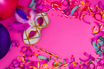 Carnival. Festive background with copy space. Carnival mask with feathers on a pink background with tinsel, balloons, multi-colored sweets. Mardi Gras. Brazilian.