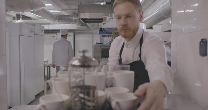 Waiter taking tray with dirty dishes in restaurant kitchen