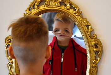 The child reflected in a distorting mirror. A fun reflection of the boy. Children's entertainment