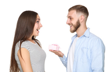 Young man giving gift box to his girlfriend on white background