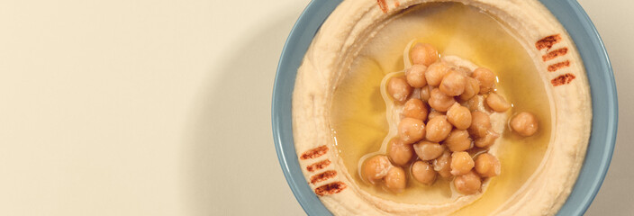 Panoramic shot of hummus plate with copy space on beige background