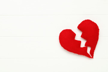 Broken fabric heart on white wooden table