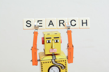 Search engine robot is looking for the best online website metaphor with toy robot on computer...