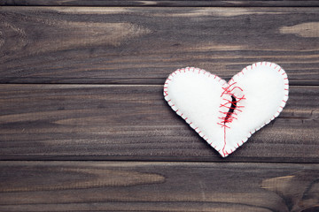 Broken white fabric heart on brown wooden table