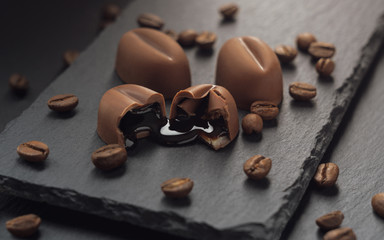 Liquor leaked from Broken chocolate piece with coffee beans on black stone plate