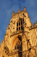 Fototapeta premium side view of one of the towers at the front of york minster in sunlight against a blue cloudy sky