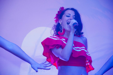 Sexy young girl singer singing. Contrast silhouette. Sexy singer girl singing and dancing. sexy female in red concert dress. dancing on mexican holiday fiesta party. various popular music genres