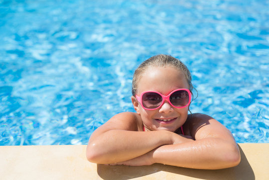 Beautiful little girl with sunglasses relaxing in the swimming pool