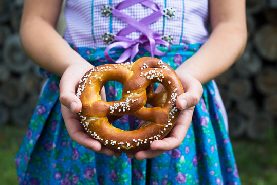 Close up of pretzel in the girl hands wearing a traditional bavarian clothes during Oktoberfest in Germany .