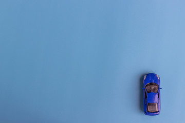 Little blue car. Children’s toy on a blue background. Flat lay. Top view. Copy space for text