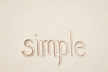 Simple message of simplicity handwritten outdoors on clean smooth sand beach