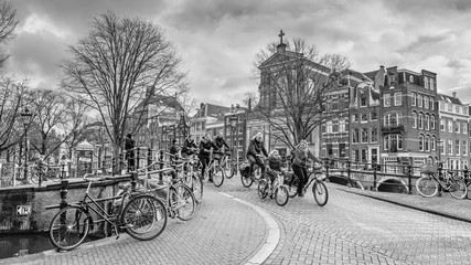 Cityscape on a winter day, in black-and-white color - view on the group of cyclists in the historic center of Amsterdam, The Netherlands