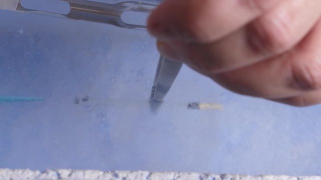 Closeup of embryologist's hands using laboratory tools during vitrification procedure of human embryo in reservoir with liquid nitrogen. Professional work of laboratory assistant for freezing ovum