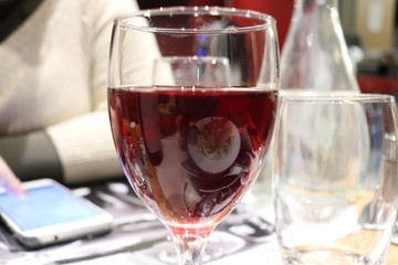 Verre de vin rouge sur une table à côté d'un téléphone portable