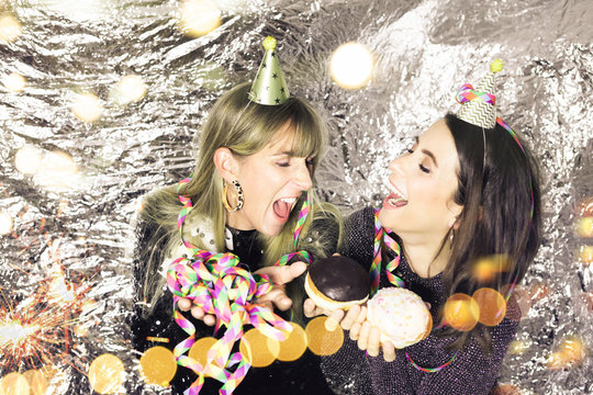 Portrait of 2 pretty party beauties with carnival donuts and confetti