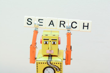 Search engine robot is looking for the best online website metaphor with toy robot on computer...
