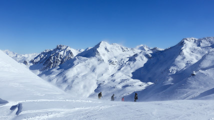 Fototapeta na wymiar Skiers on top of snowy slope on a windy day, in skiing resort of 3 Valleys, Val Thorens , Alps, France .